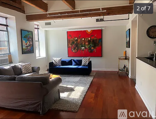 A living room with a grey couch and a red painting on the wall.
