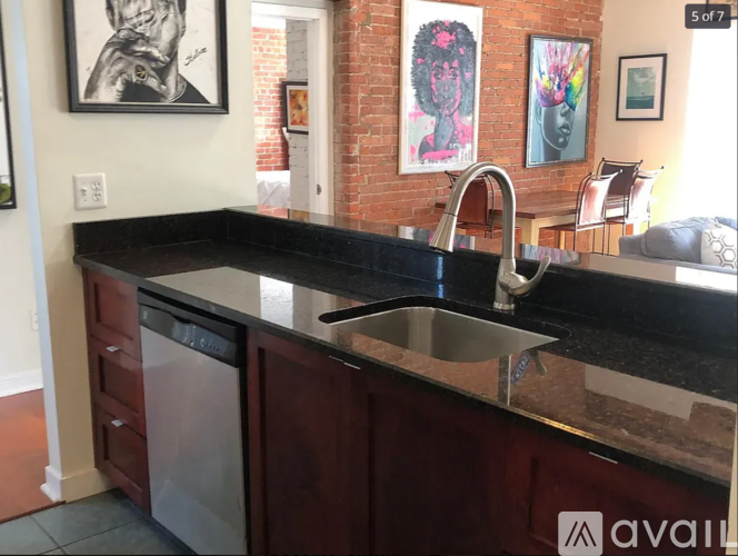 A kitchen with a black countertop and a stainless steel dishwasher.