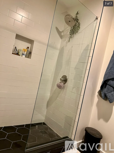 A bathroom with a glass shower door and a towel hanging on the wall.