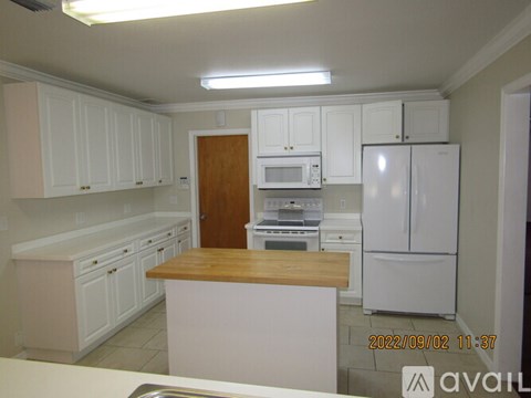 A kitchen with white cabinets and appliances, a wooden island, and a date stamp of 2022/09/02 11:37.