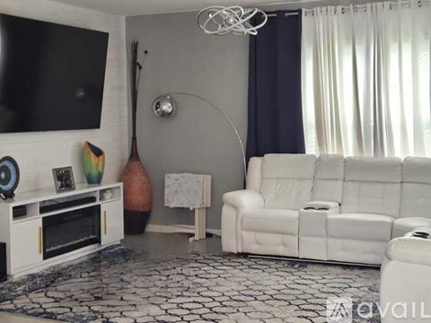 A living room with a white couch and a television on the wall.
