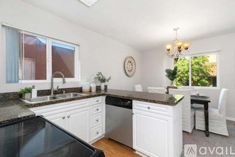 A kitchen with white cabinets and a black countertop.