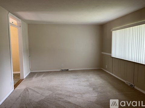 A room with a carpeted floor and a window with blinds.