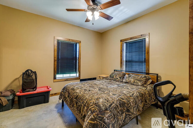 A bedroom with a camouflage bedspread and a ceiling fan.