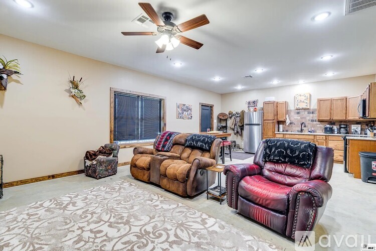 A living room with a brown leather couch and a ceiling fan.