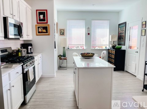 A kitchen with white cabinets and a white island.
