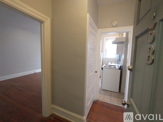 A hallway with a door on the right and a washer and dryer in the doorway.