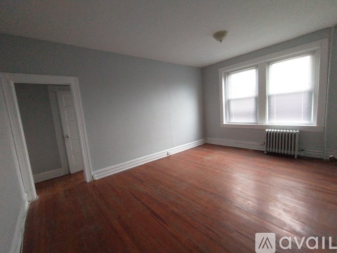A room with wooden floors and a window with blinds.