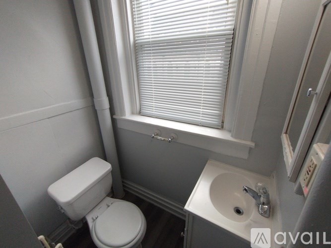 A small bathroom with a toilet, sink and window.
