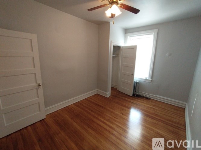 A room with wooden floors and a window with blinds.
