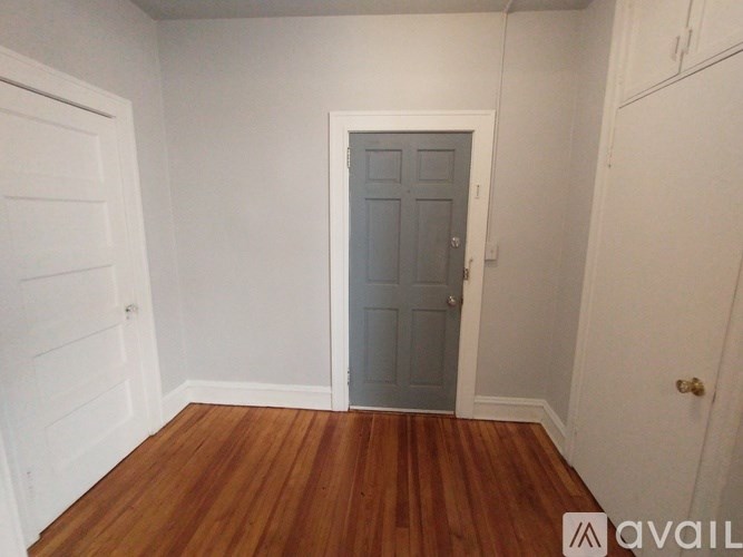 A room with wooden floors and a window with a view of a tree.
