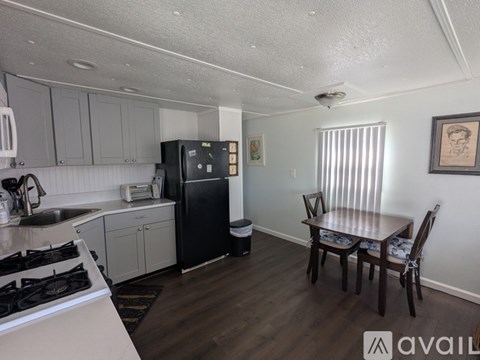 A kitchen with a black fridge and a dining table with chairs.
