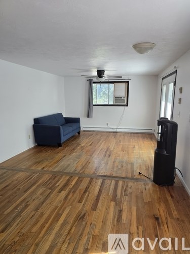 A living room with a blue couch and wooden floors.