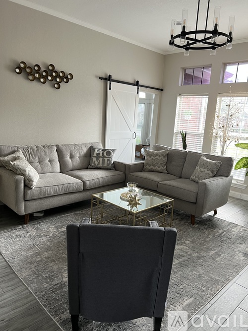 A living room with a grey couch and a glass coffee table.