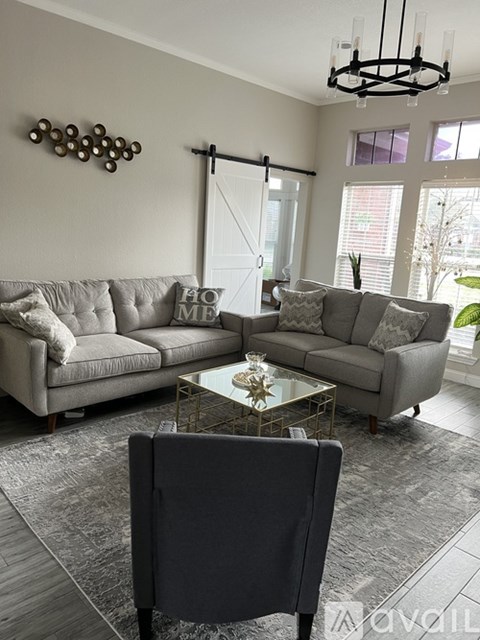 A living room with a grey couch and a glass coffee table.