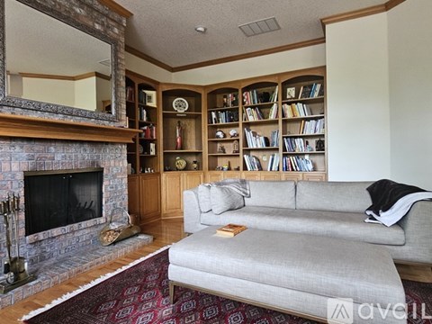 A living room with a grey couch, a fireplace, and a bookshelf filled with books.