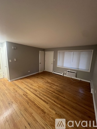 A room with wooden flooring and a refrigerator in the corner.