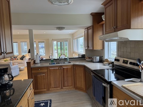 A kitchen with wooden cabinets and black countertops is available for rent.
