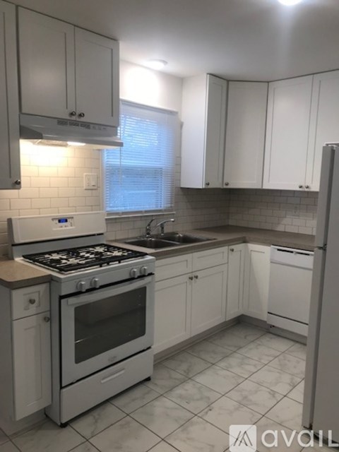 A kitchen with white cabinets and a stove top oven.