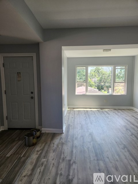 A room with a grey door and a window with a view of trees.