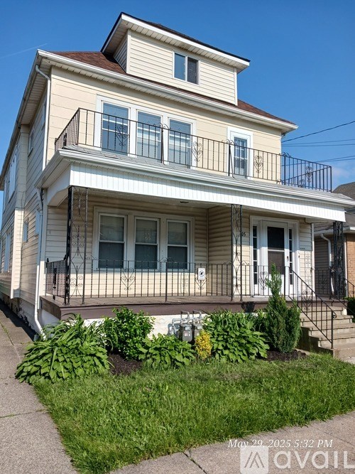 A two-story house with a balcony and a small garden in front.