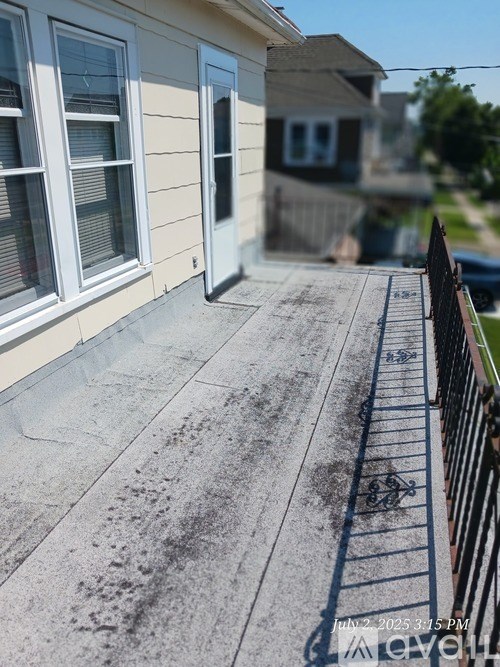A concrete patio with a black railing and a house in the background.