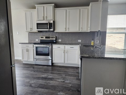 A kitchen with white cabinets and a black refrigerator.