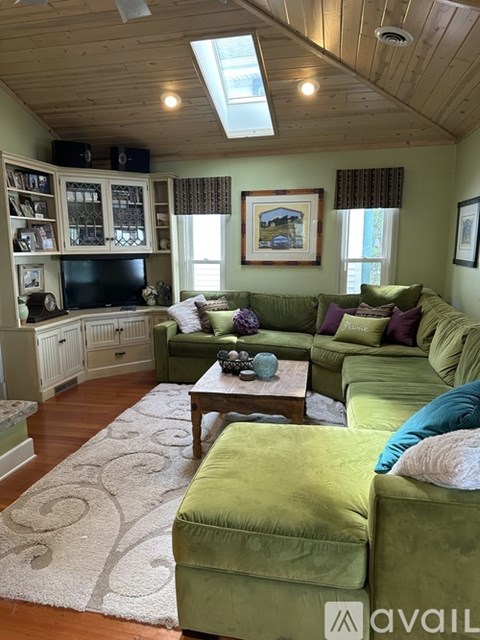 A living room with green couches and a wooden ceiling.