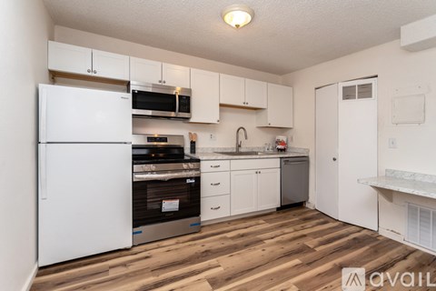 A kitchen with white appliances and wooden floors.