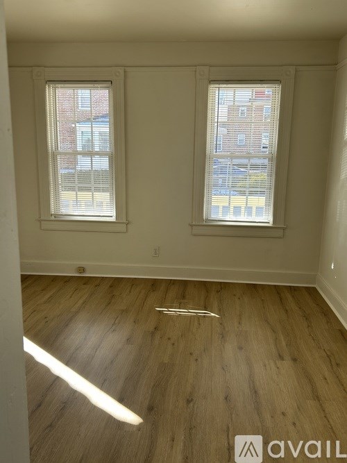 A room with wooden floors and two windows.