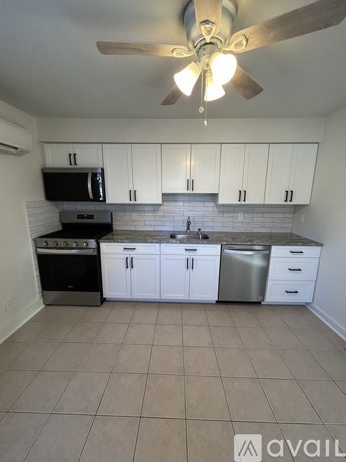 A kitchen with white cabinets and a black microwave.