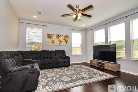 A living room with a grey sofa and a television on a wooden stand.