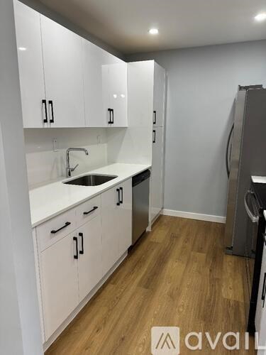 A kitchen with white cabinets and a wooden floor.