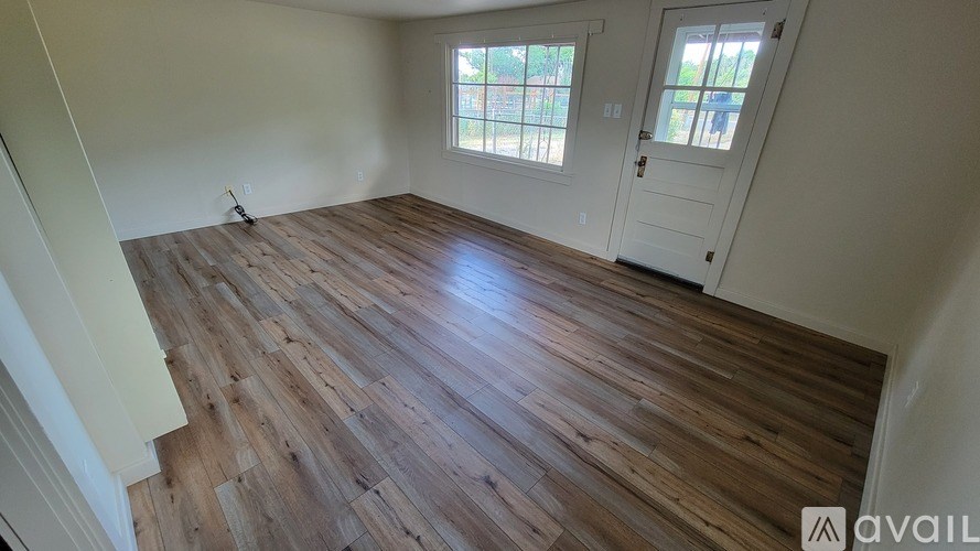 A wooden deck with a table and chairs is surrounded by greenery.