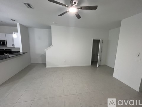 A spacious room with a ceiling fan and a kitchen area with a stove and cabinets.