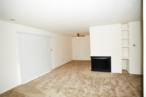 an empty living room with a fireplace and white walls