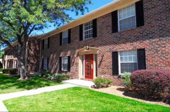 the front of a brick house with a red door
