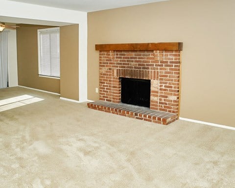 an empty living room with a brick fireplace