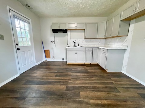 A kitchen with white cabinets and a wooden floor.
