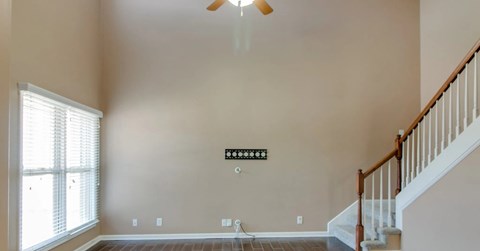 A living room with a staircase and a ceiling fan.