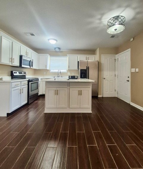 A kitchen with white cabinets and a brown floor.