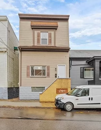 A white van is parked in front of a two-story house.