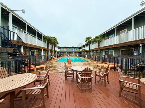 A wooden deck with chairs and a pool in the middle of it.