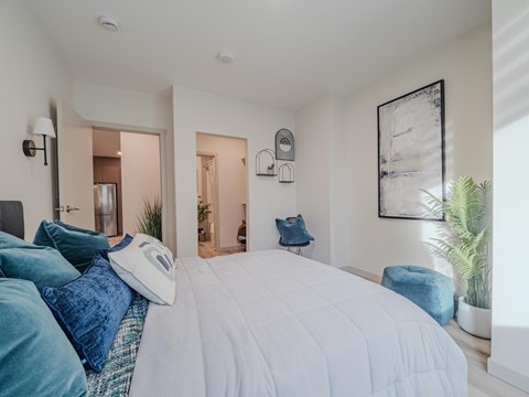 A bedroom with a large bed and a potted plant.
