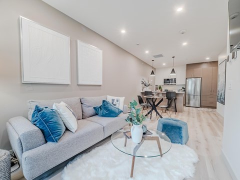 A modern living room with a grey sofa and a glass coffee table.