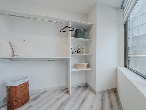 A room with a white wall and a window with a view of a building outside.
