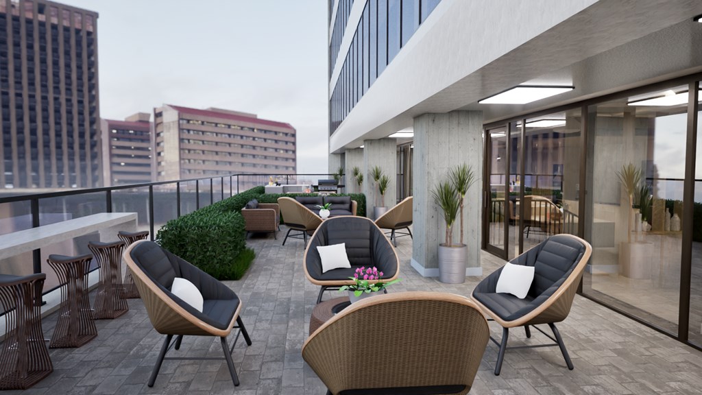 A patio with chairs and tables overlooking a cityscape.