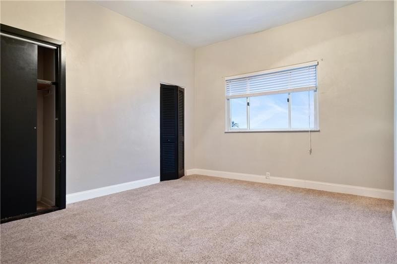 A room with a window and a carpeted floor.