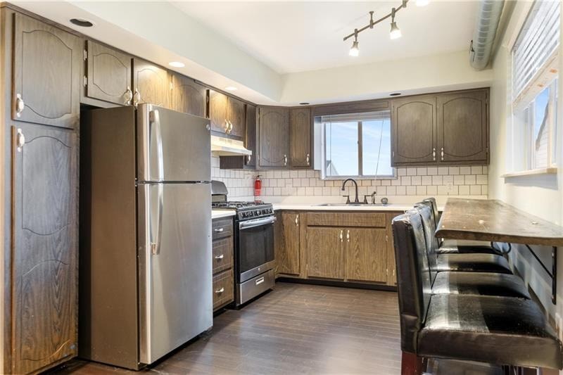 A kitchen with a refrigerator, oven, and sink.