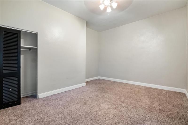 A room with a carpeted floor and a closet with a sliding door.